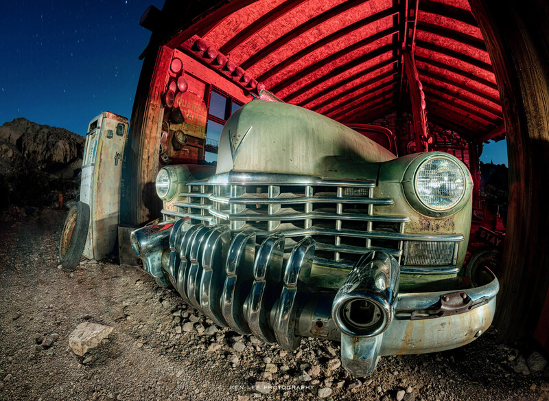 Vintage truck front end with weathered chrome grille under a red metal structure.