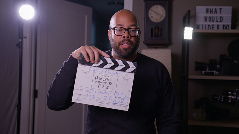 Man holding film clapperboard in a studio setting with professional lighting.