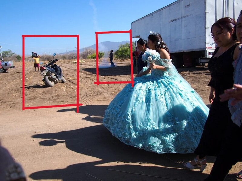 Woman in turquoise ball gown dress stands in desert landscape with red frame markers visible in background.