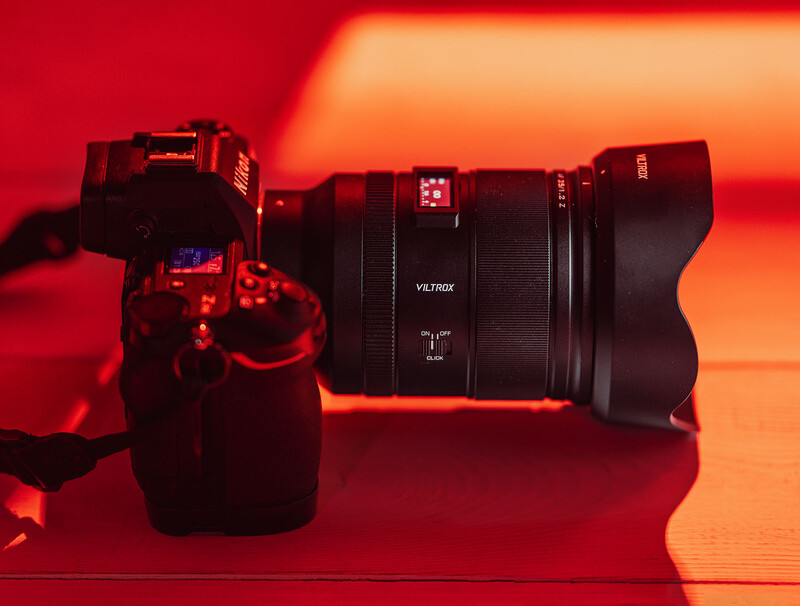 Video camera and telephoto lens arranged on a red and orange gradient surface.