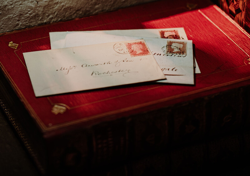 Antique letters and envelopes with red wax seals arranged on a crimson velvet display surface.