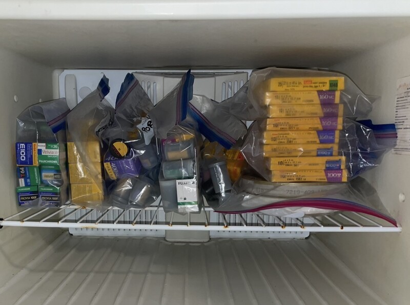 Freezer shelf containing various packaged food items and frozen goods organized in containers.