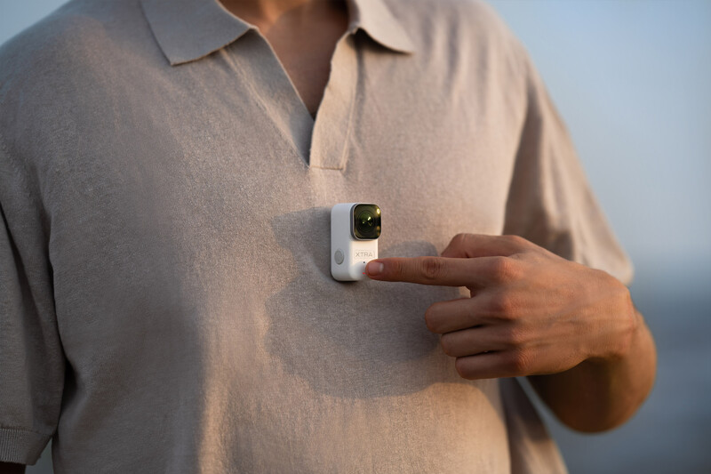 Person in beige polo shirt holding a white smartwatch against their chest.