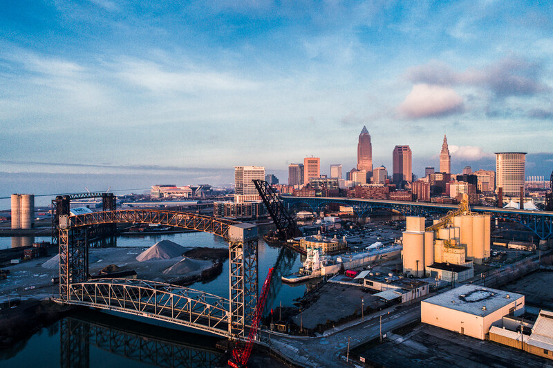 Industrial waterfront with red crane and city skyline at golden hour.