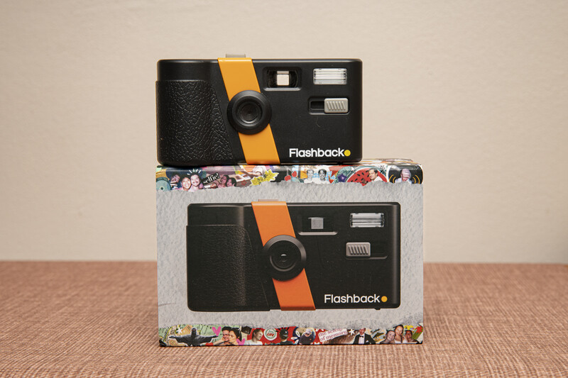 Two Flashback instant cameras stacked vertically, with black bodies and orange stripe details.