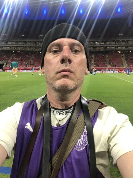 Man wearing purple and white athletic gear at a stadium during a match.