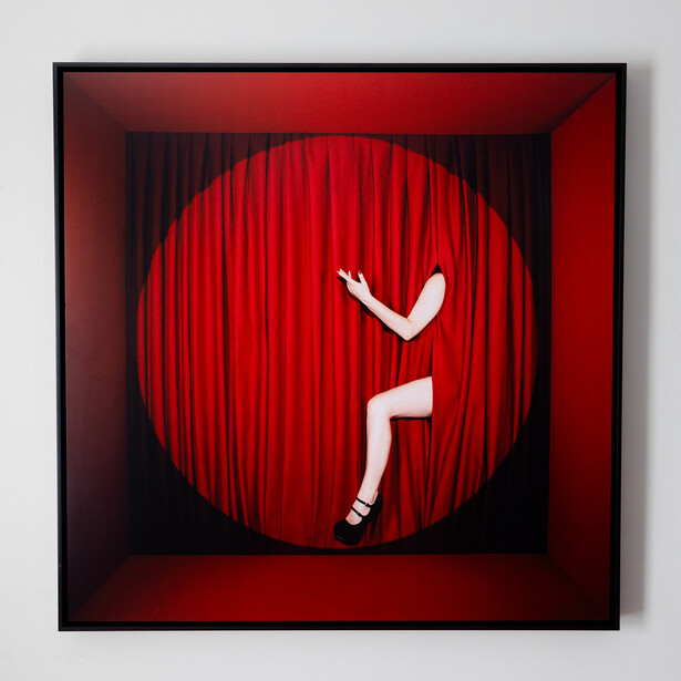 White silhouette of a person falling against a red circular background with vertical curtain texture.