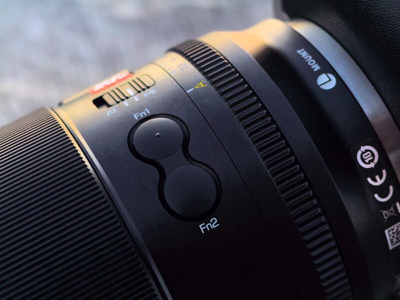 Close-up of camera lens barrel showing focus ring with depth-of-field scale markings and aperture indicators.