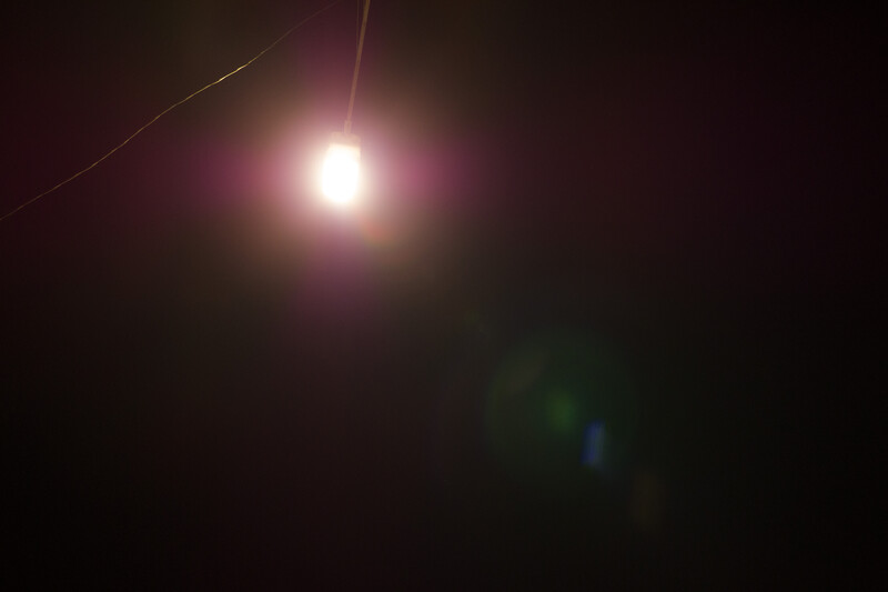 Bright light source with lens flare and purple glow against dark background.