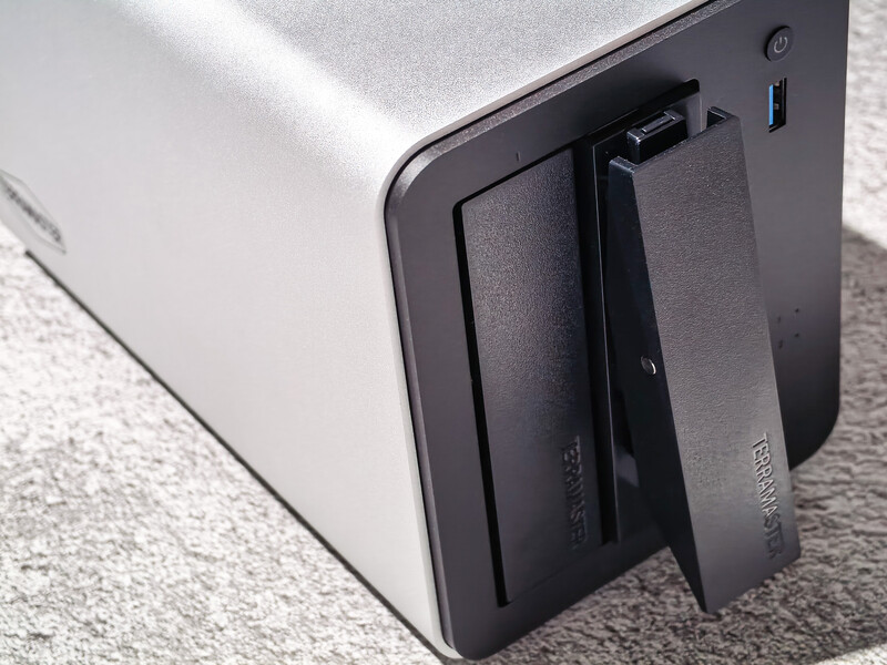 External hard drive with open compartment showing dual drive bays on carpeted surface.