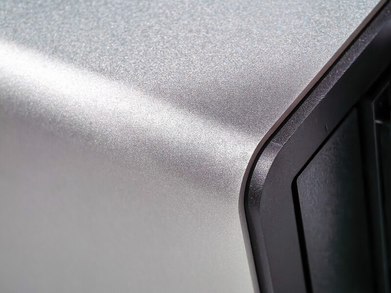 Close-up of a metallic silver surface with specular highlight and dark rubber trim edge.