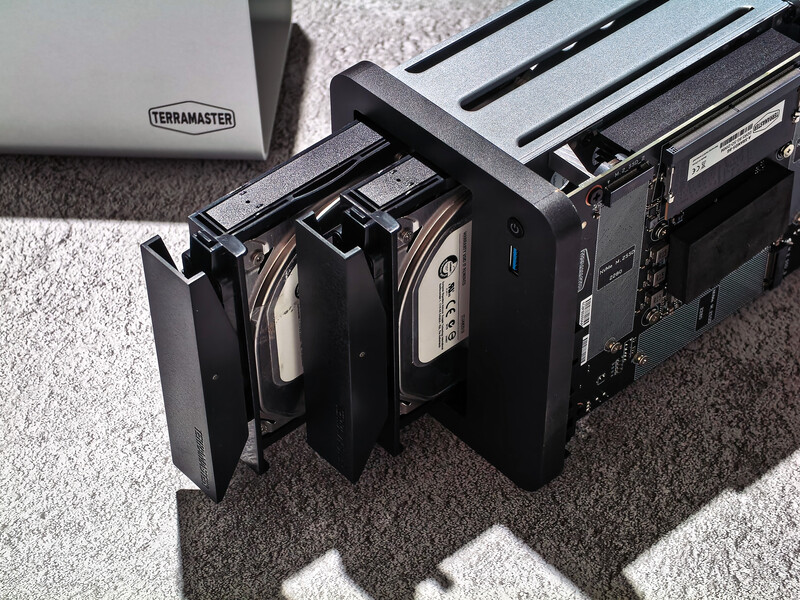 Three external hard drives with open bays mounted on a storage solution, photographed on a carpet with studio lighting.