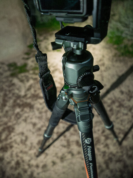 Tripod with ball head and monitor mounted on top, viewed from above on pavement.