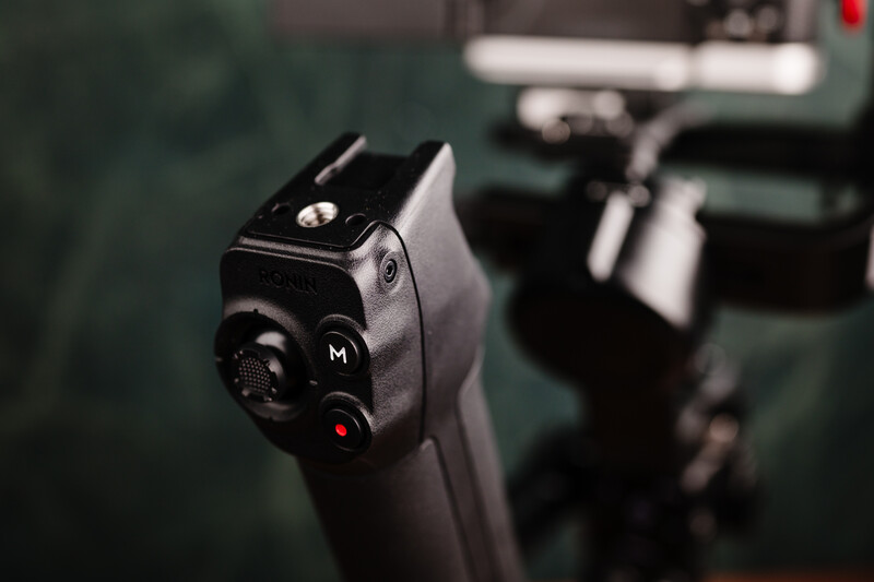 Close-up of a firearm's rear sight assembly with blurred background showing additional weapons.
