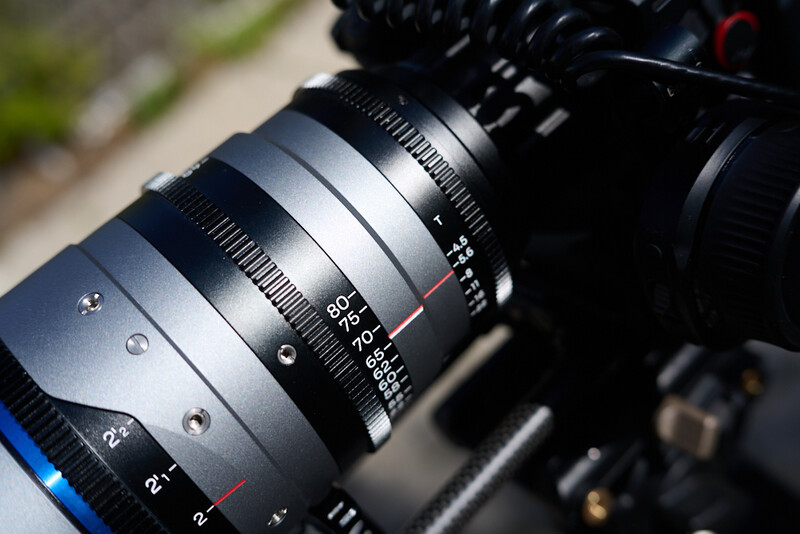Close-up of a cinema lens mounted on a camera body, showing focus ring markings and mechanical details.