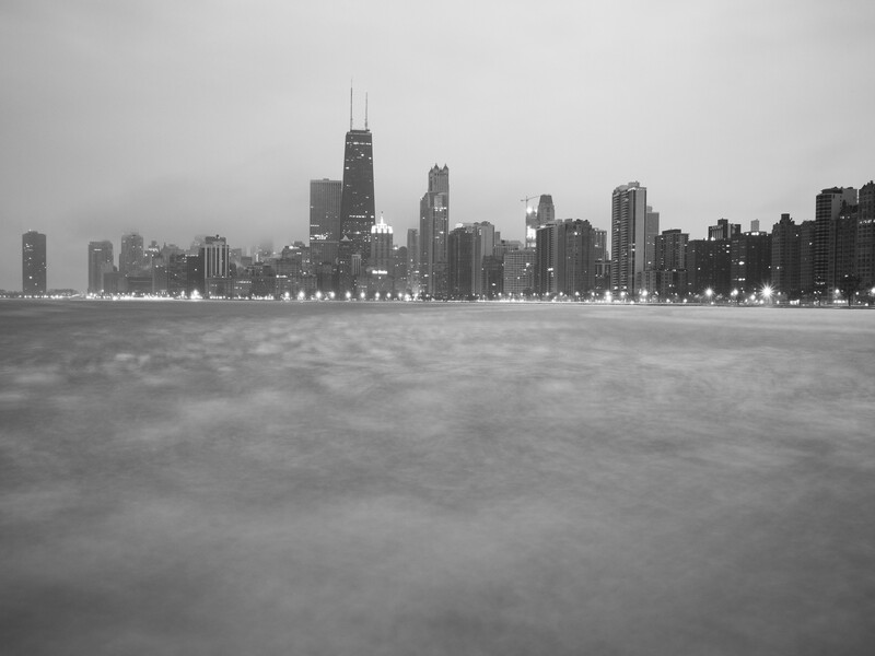 Black and white long exposure photograph of pancake ice in front of Chicago skyline