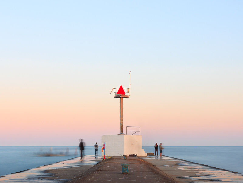 Long exposure sunrise photo of fishers on a pier in Lake Michigan