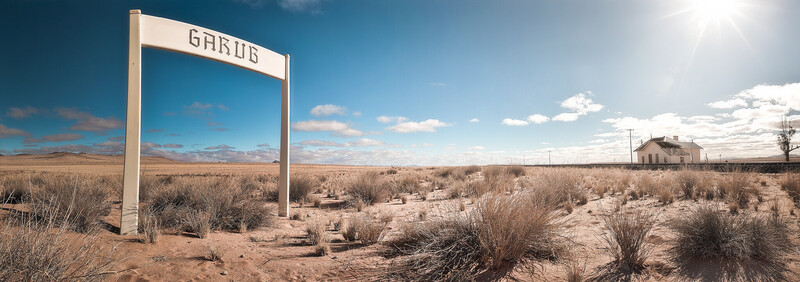 Large white gate frame standing alone in vast desert landscape with sparse vegetation.
