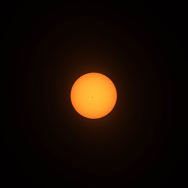 Large orange sun against a completely dark background with subtle glow effect.