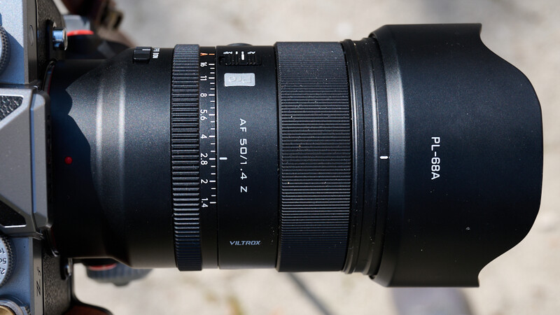 Viltrox 50mm f/1.4 autofocus lens with lens hood attached, showing aperture ring and focus distance scale.