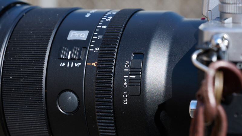 Close-up of a manual focus lens showing AF/MF switch, aperture ring, and focus distance markings.