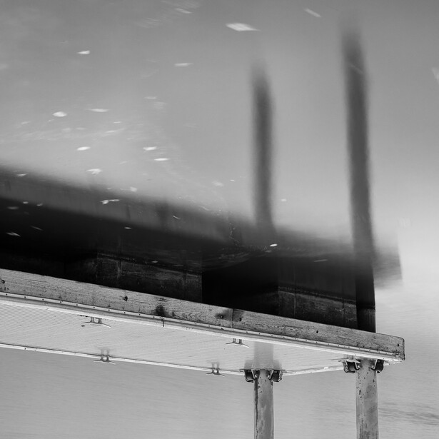 Black and white abstract photograph of a dock and its reflection
