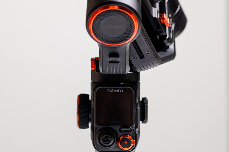 Overhead view of a black and orange handheld camera gimbal stabilizer on white background.