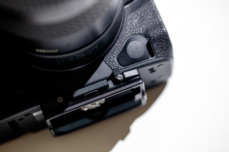 Close-up of a camera body's grip and shutter release button with textured rubber surface.