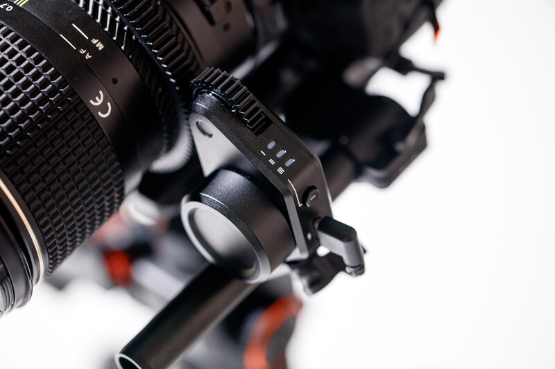 Close-up of a cinema camera lens with focus ring and depth of field markings visible.