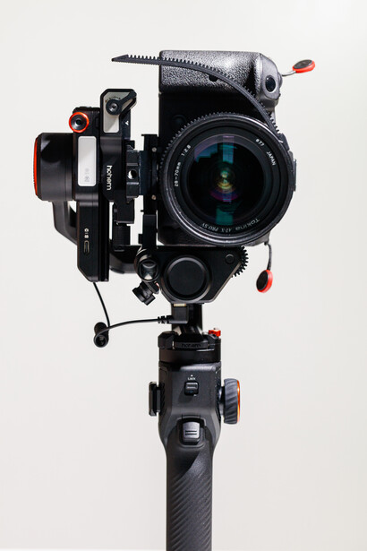 Professional cinema camera rig with matte box and follow focus mounted on tripod head against white background.