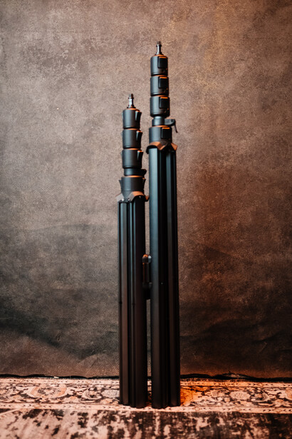 Three black ammunition cartridges of varying sizes arranged vertically against a textured brown backdrop.