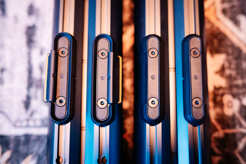 Four metallic handles mounted in parallel on blue and white striped surface with blurred warm-toned background.