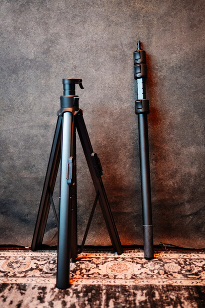 Two tripods leaning against a textured wall beside a patterned floor.