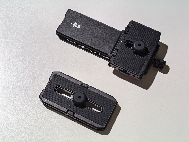 Two black quick-release camera mounting plates with adjustment knobs displayed against a light background.