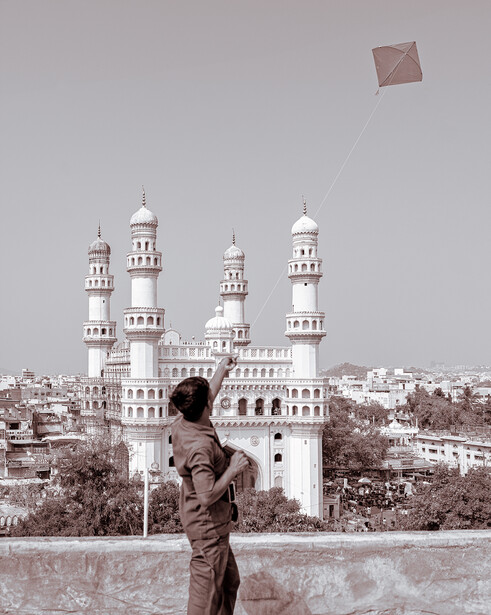 Young man flying kite near Charminar monument in Hyderabad.