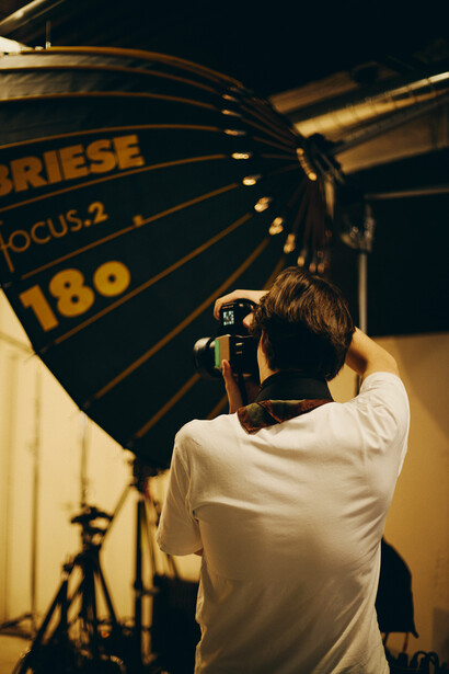 Photographer holding a large reflector with focus marking during studio lighting setup.