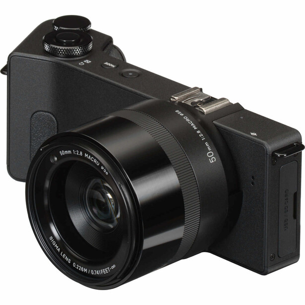 Black mirrorless camera with attached zoom lens, shown at three-quarter angle against white background.