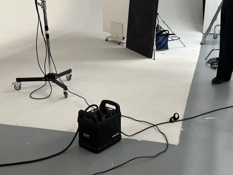 Professional photography studio setup with softbox lighting, black equipment case, and white seamless backdrop.