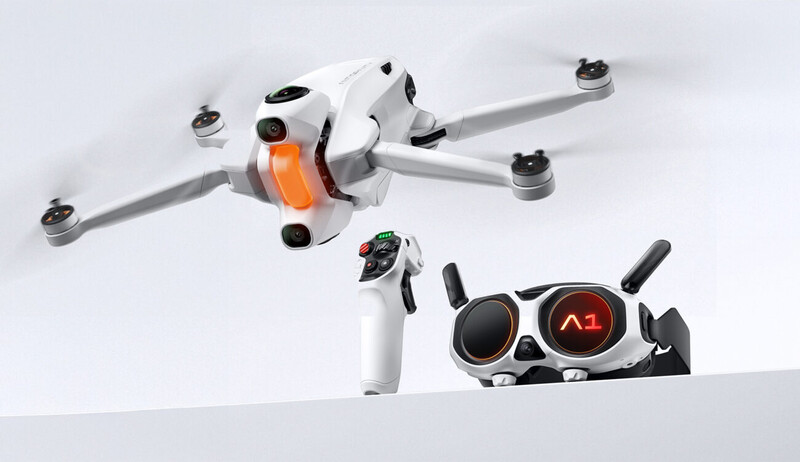 Drone with white body and orange accents displayed with its remote controller on white background.