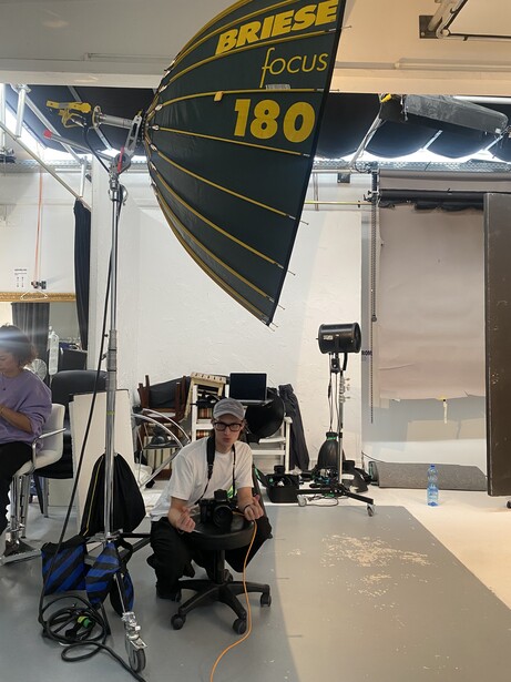 Large parabolic reflector with Fresnel lens mounted on lighting stand in studio space.
