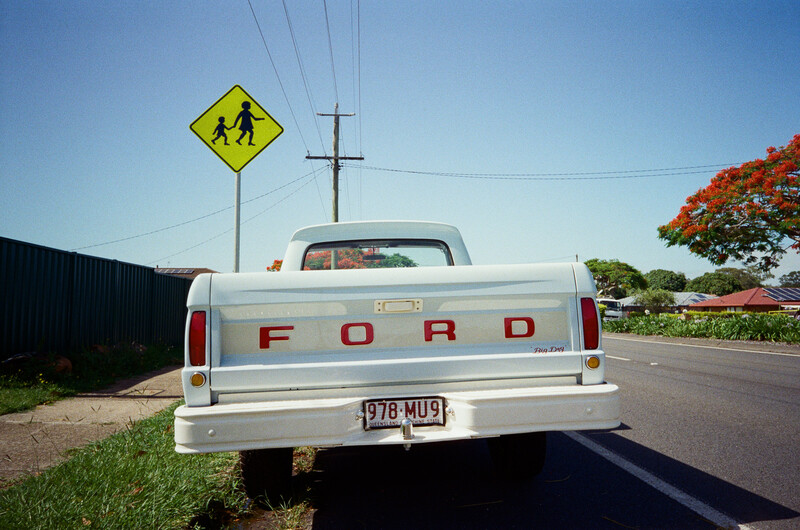 Rear view of a white Ford pickup truck parked on a residential street under clear skies.