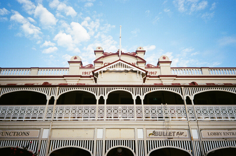 Victorian-era building facade with striped awnings and ornate architectural details under blue sky.