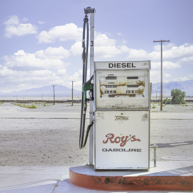 Abandoned vintage diesel gas pump in desert landscape under blue sky.