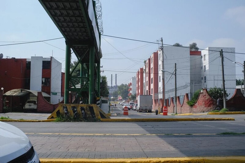 Industrial underpass with red and white buildings under overcast sky.