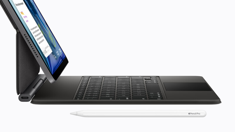 Digital tablet mounted on keyboard stand with stylus pen positioned on black desk surface.
