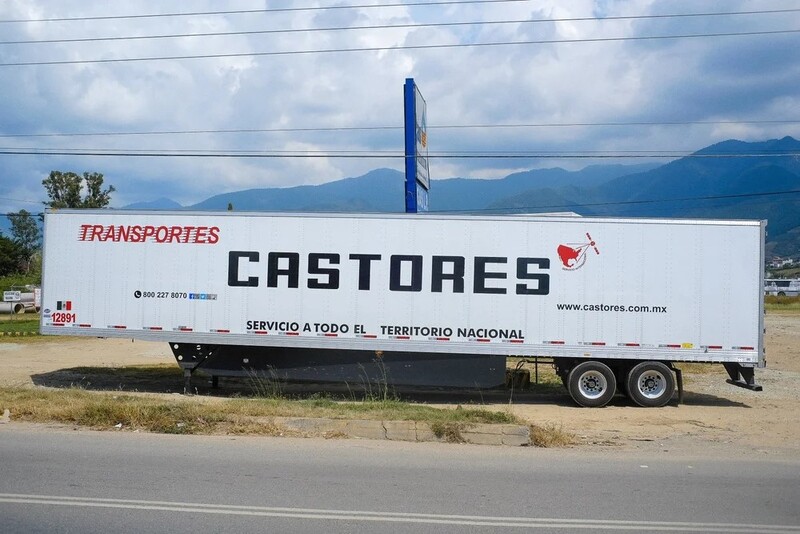 White commercial transport truck with Castores branding parked on roadside with mountains in background.