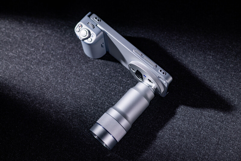 Silver mirrorless camera with attached telephoto lens on dark textured surface.
