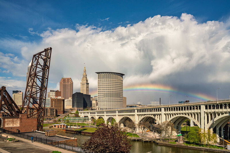 Cleveland skyline with arched bridge and dramatic cloudscape featuring a rainbow.