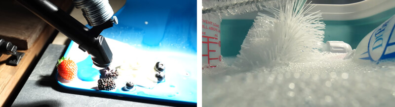 Macro photography setup with strawberry and metal objects on blue surface under studio lighting.