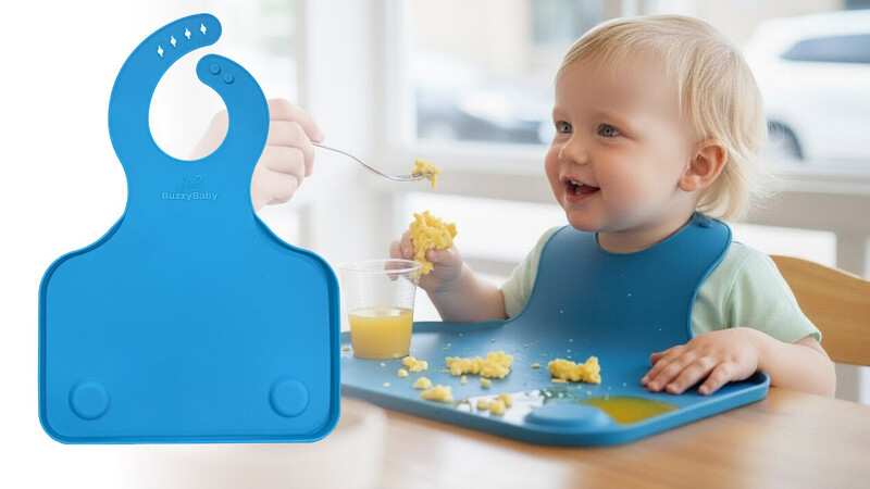 Toddler eating from a plate while wearing a blue silicone bib with food debris visible.